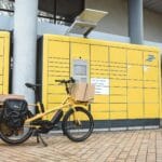 Żółty rower cargo z paczkami przy automacie paczkowym we Francji