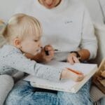Mama z kilkuletnią córką rysują razem przy stole w domu