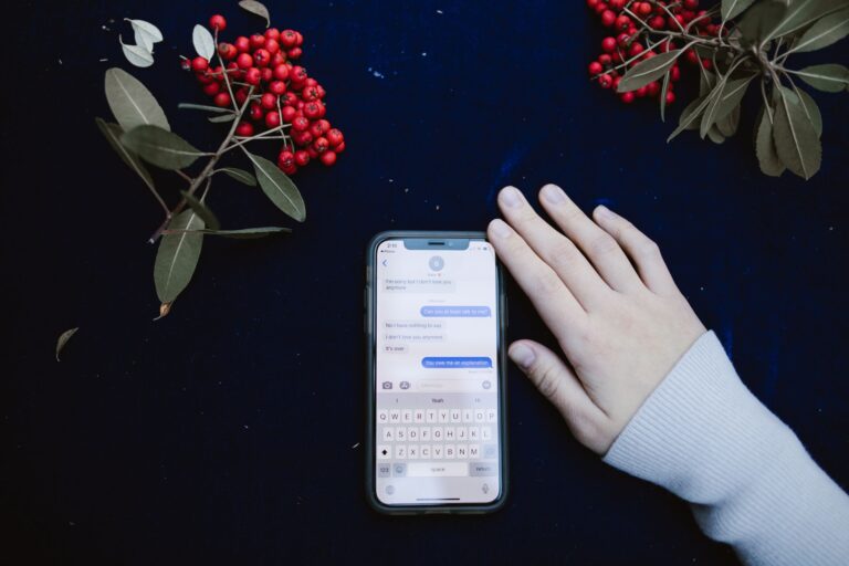 Dłoń obok smartfona z rozmową SMS i czerwonymi jagodami