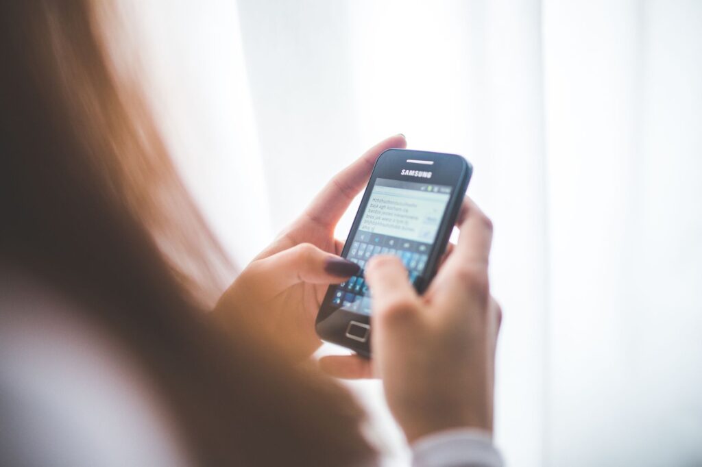 Młoda kobieta wpisująca wiadomość na smartfonie Samsung w domu